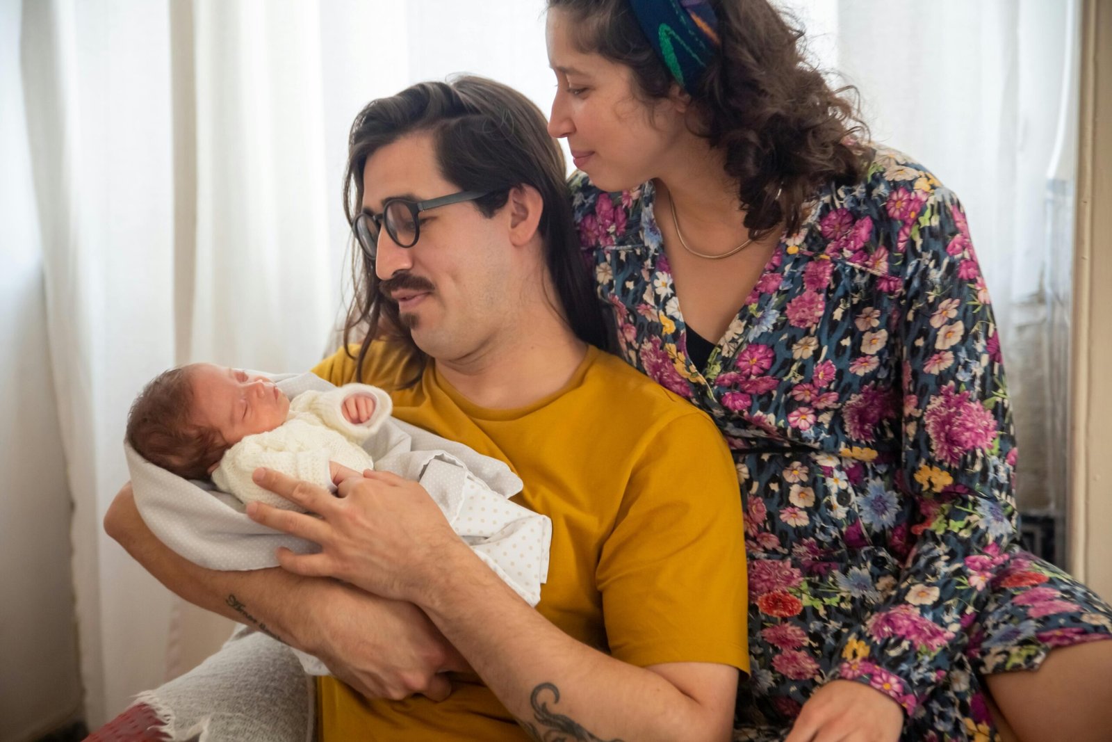 Heartwarming family portrait featuring parents lovingly holding their newborn baby, capturing tender moments.